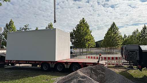 Trafostation für E-Ladepark an der Allianz Arena wird angeliefert mittels eines Anhängers