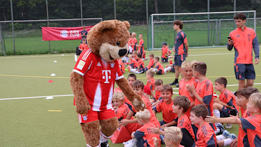 Berni beim Fußballcamp in Berlin; klatscht die Kids ab, die auf dem Boden sitzen