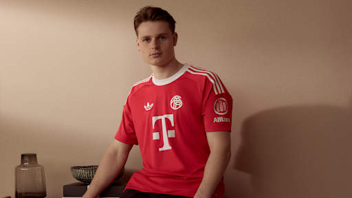 Jonas Urbig trägt das neue Champions League-Torwarttrikot des FC Bayern in Rot mit historischem Vereinslogo.