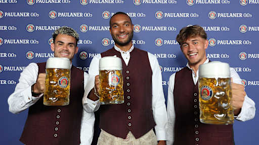 Luis Diaz, Jonathan Tah und Tom Bischof stoßen mit einem Maßkrug an.