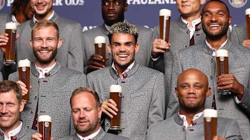 Konrad Laimer, Luis Diaz und Jonathan Tah lachen mit einem Weißbierglas in der Hand