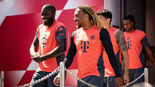 Dayot Upamecano und Sacha Boay lächelnd auf dem Weg zum Trainingsplatz des FC Bayern.