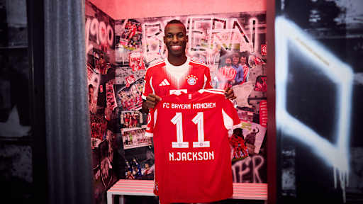 Nicolas Jackson hält ein FC Bayern Trikot mit der Nummer 11 und N. Jackson