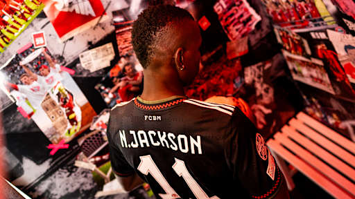 Nicolas Jackson steht mit dem Rücken zur Kamera und trägt ein FC Bayern Trikot mit N.Jackson und Nummer 11
