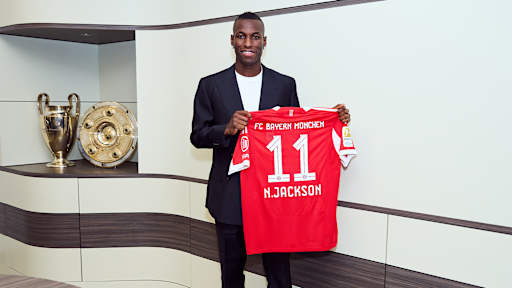 Nicolas Jackson hält ein FC Bayern Trikot mit der Nummer 11 und N. Jackson