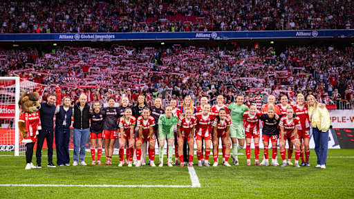 Die FC Bayern Frauen in einem Gruppenfoto vor der Südkurve der Allianz Arena mit Fans im Hintergrund.