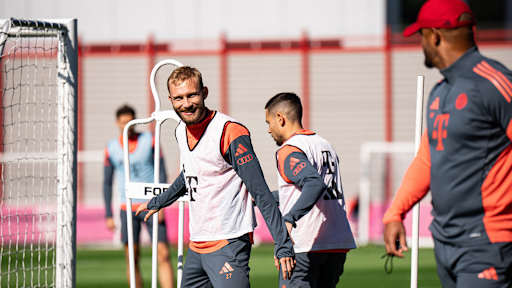 Konrad Laimer blickt lächelnd zu Vincent Kompany im Abschlusstraining des FC Bayern vor dem Spiel bei Eintracht Frankfurt.