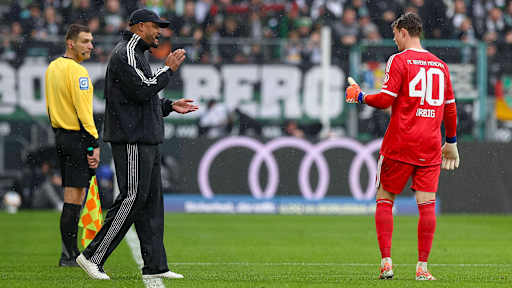 Trainer Vincent Kompany spricht mit Torwart Jonas Urbig im Bundesliga-Spiel des FC Bayern bei Borussia Mönchengladbach.