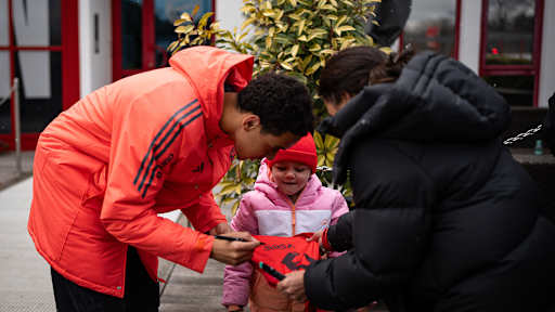 Jamal Musiala unterschreibt ein Trikot von einem kleinen Mädchen