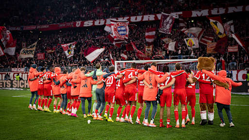 Spieler des FC Bayern hüpfen Arm in Arm vor der Südkurve nach dem Sieg gegen Freiburg.