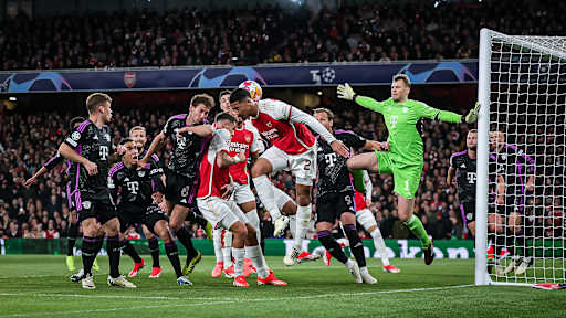 Various FC Bayern players in black and Arsenal players in red go for the ball. Manuel Neuer in green stands in goal.
