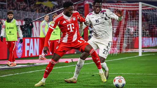 Alphonso Davies im Zweikampf mit Ball am Fuß während des Bundesliga-Heimspiels des FC Bayern gegen den 1. FSV Mainz 05