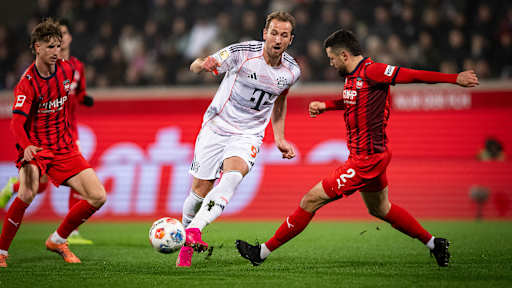 Harry Kane am Ball wird attackiert von seinem Gegenspieler im Bundesliga-Spiel des FC Bayern in Heidenheim.