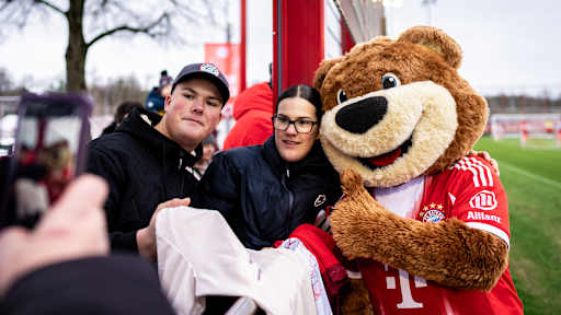 Maskottchen Berni posiert mit Fans im öffentlichen Training des FC Bayern vor Fans