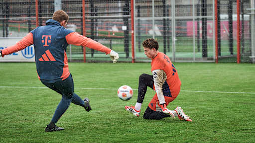 Jonas Urbig pariert einen Schuss von TW-Trainer Michael Rechner  im Training des FC Bayern