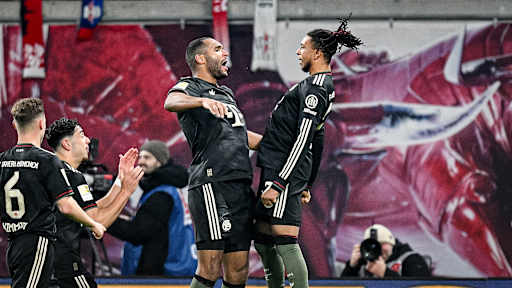 Jonathan Tah und Michael Olise jubeln zusammen während des Gastspiels des FC Bayern in der Bundesliga bei RB Leipzig