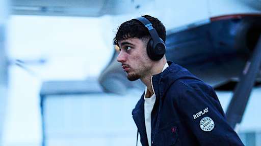 Aleksandar Pavlovic steigt im blauen Replay-Outfit in das Flugzeug.