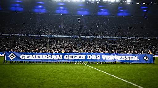 Spieler und Mitarbeiter beider Vereine halten ein Banner vor dem Gastspiel des FC Bayern in der Bundesliga beim Hamburger SV