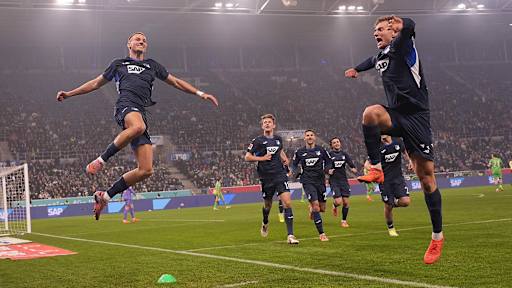 Tim Lemperle and Fisnik Asllani leap into the air in blue Hoffenheim jerseys.