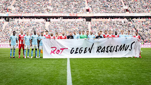 Die Spieler halten ein Banner mit der Aufschrift "Rot gegen Rassismus" vor dem Heimspiel des FC Bayern in der Bundesliga gegen den 1. FC Union Berlin