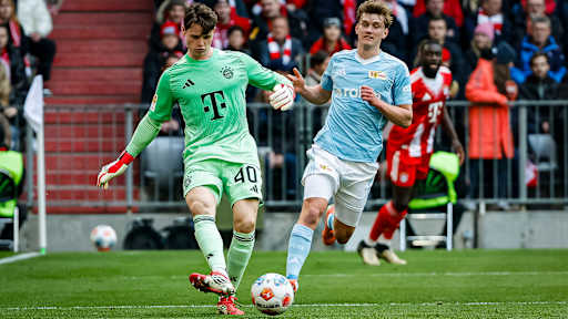 Jonas Urbig kommt vor Aljoscha Kemlein an den Ball während des Heimspiels des FC Bayern in der Bundesliga gegen den 1. FC Union Berlin