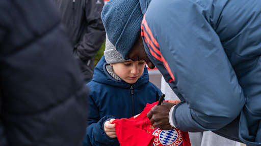 Alphonso Davies gibt einem kleinen Jungen ein Autogramm