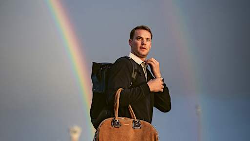 Manuel Neuer auf dem Rollfeld mit Reisetasche vor einem Regenbogen