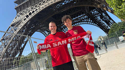 Zwei Bayern-Fans halten einen Schal hoch vor dem Eiffelturm in Paris