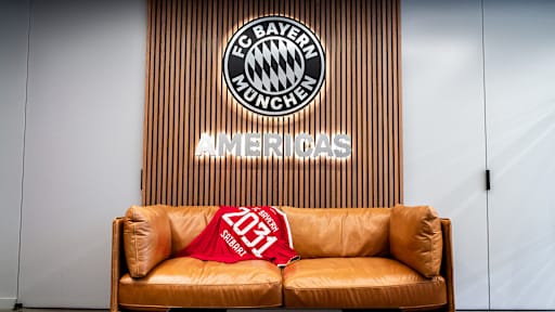 Auf einer Couch liegt ein rotes FC Bayern-Trikot mit der Aufschrift Saibari 2031