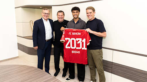 Jan-Christian Dreesen, Max Eberl, Nathaniel Brown und Christoph Freund stehen nebeneinander und halten ein FCB-Trikot mit 2031 Brown