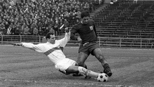 Ein Stuttgarter Spieler versucht Gerd Müller den Ball mit einer Grätsche vom Fuß zu spitzeln