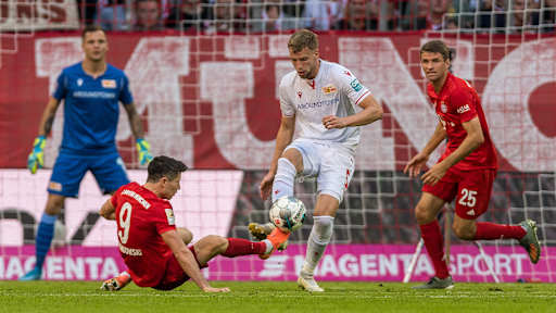 Robert Lewandowski setzt gegen einen Spieler von Union zur Grätsche an