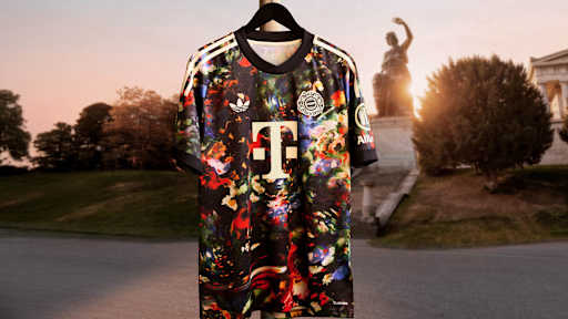 Das neue FC Bayern-Wiesn-Trikot 2026/27 mit farbenfrohem floralen Muster hängt vor der Bavaria auf der Theresienwiese