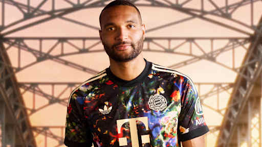 Jonathan Tah  trägt das neue FC Bayern-Wiesn-Trikot 2026/27 mit farbenfrohem floralen Muster, im Hintergrund ist die Münchner Hackerbrücke zu sehen