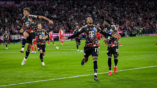 Michael Olise, Tom Bischof und Alphonso Davies stürmen auf die Kurve zu während des Bundesligaspiels zwischen dem FC Bayern und Union Berlin