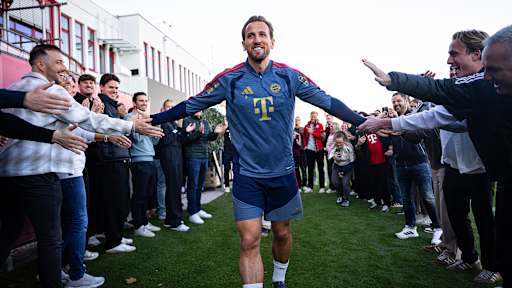 Harry Kane durchläuft lächelnd ein Spalier von FCB-Mitarbeitenden vor dem Abschlusstraining des FC Bayern vor dem DFB-Pokal-Spiel gegen Magdeburg