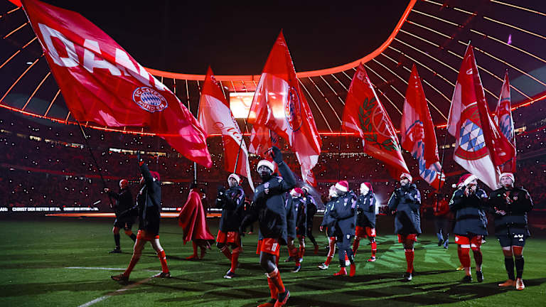 Nach dem letzten Heimspiel 2023 laufen die FC Bayern-Spieler mit Fahnen über den Rasen der Allianz Arena