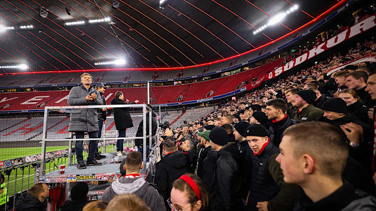 Startenor Jonas Kaufmann blickt von einem Podest auf die Fans in der Südkurve in der Münchner Allianz Arena.