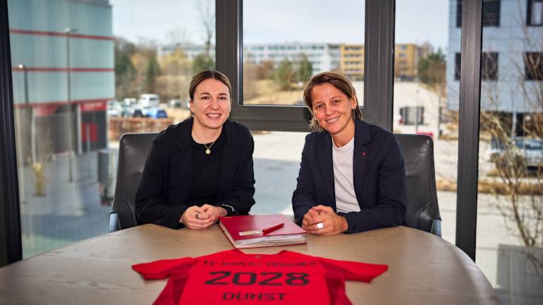 Barbara Dunst und Bianca Rech sitzend bei der Vertragsunterschrift am FC Bayern Campus.