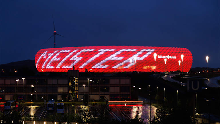 Allianz Arena leuchtet bei Nacht in Rot mit weißem Schriftzug Meister