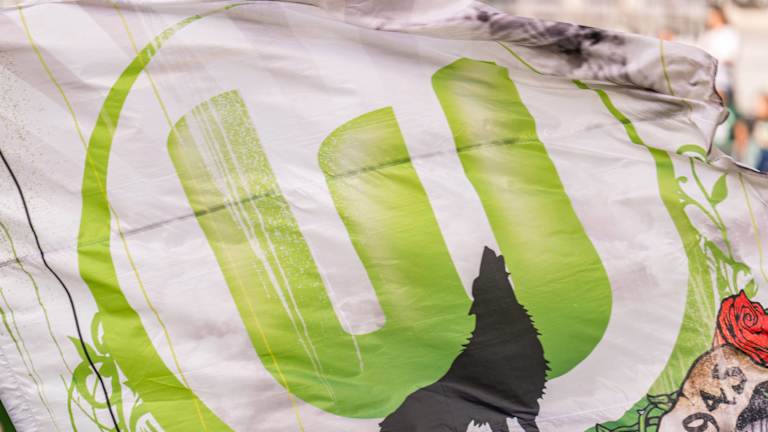 Eine Flagge mit dem Logo des VfL Wolfsburg. Im Vordergrund steht die Silhouette eines heulender Wolfs.