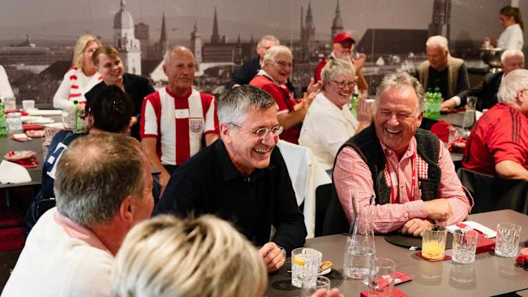 Herbert Hainer lacht inmitten von FC Bayern-Fans