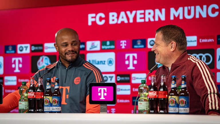 Vincent Kompany und Max Eberl schauen sich im Pressetalk des FC Bayern lächelnd an