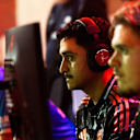 Dos hombres están sentados frente al televisor con auriculares y juegan a videojuegos.