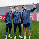 Luis Diaz, Jonas Urbig und Josip Stanisic nehmen ein Selfie gemeinsam auf.