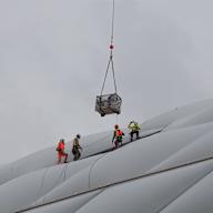 Arbeiter nehmen auf dem Dach der Allianz Arena eine Ladung entgegen, die zu ihnen abgeseilt wird.