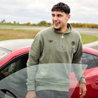Aleksandar Pavlovic steeht lachend vor einem  roten Audi