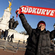 Ein FC Bayern Fan hält einen Schal mit Südkurve 1972 hoch
