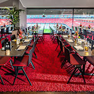 Eventbox - niedrige Tische vor Glasfront mit Blick ins Stadioninnere