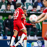 Tom Bischof springt auf Michael Olise nach dem 1:= im Bundesliga-Spiel des FC Bayern beim VfL Wolfsburg